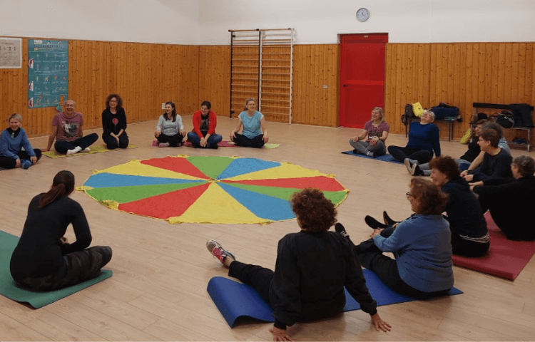 adulti seduti in cerchio attorno a telo colorato yoga della risata